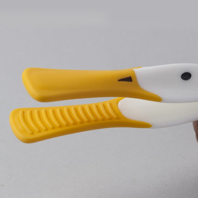Close-up of yellow and white duck-shaped toast tongs with textured grip, featuring a heat-resistant silicone beak, designed for safe serving in kitchen gadgets and accessories collections.