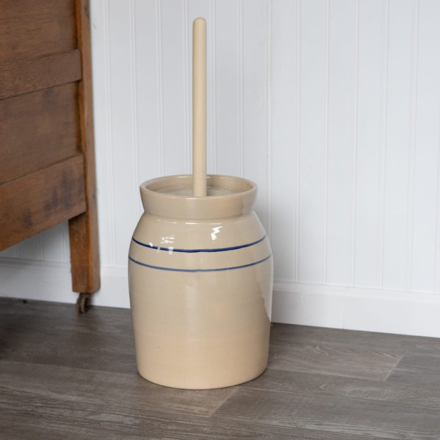Handcrafted stoneware butter churn in natural stone color featuring smooth unfinished wooden dasher and classic double blue stripes, made in USA, ideal for Kitchen & Food and Specialty Equipment collections.