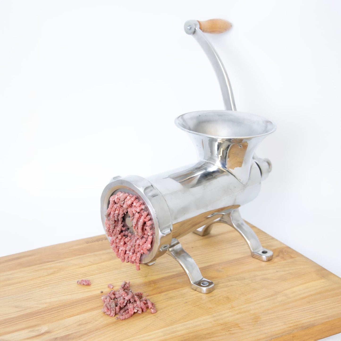 Handcrafted stainless steel kitchen meat grinder with wooden handle mounted on wooden surface, extruding fresh ground meat, featured in Kitchen & Food, Specialty Equipment, Butchering Supplies, Best Sellers collections.