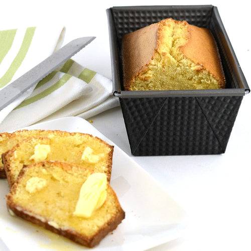 Non-stick heavy gauge steel loaf pan with corrugated texture and folded square corners, shown with a freshly baked golden loaf, featured in Kitchen & Food, Baking Supplies, and Best Sellers collections.