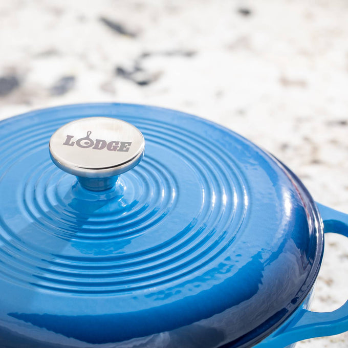 Close-up of a handcrafted enameled cast iron Dutch oven lid in glossy blue with a stainless steel knob engraved with "Lodge," featured in Kitchen & Food, Cookware, Cast Iron, Best Sellers, Bread Making Supplies, and Promo Eligible collections.