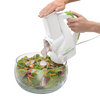 White and green electric vegetable slicer shredding radishes directly into a glass bowl of mixed fresh salad greens and shredded carrots, ideal for Kitchen & Food and Food Prep collections.