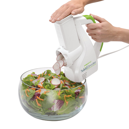 White and green electric vegetable slicer shredding radishes directly into a glass bowl of mixed fresh salad greens and shredded carrots, ideal for Kitchen & Food and Food Prep collections.