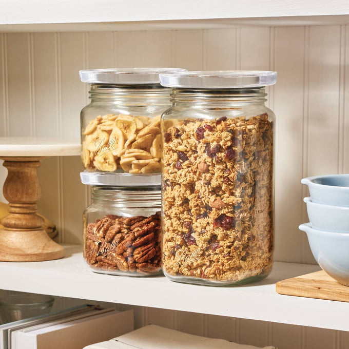 Set of clear stackable glass jars with airtight lids, filled with dried bananas, pecans, and granola, displayed on a white kitchen shelf for Home & Decor, Kitchen & Food, and Storage collections.