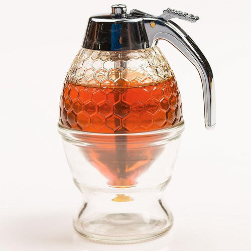 Glass honey and syrup dispenser with textured honeycomb pattern, chrome lever and plastic lid, designed for mess-free serving, ideal for Kitchen & Food and Storage and Serving collections.