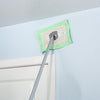 Long-handled cleaning mop with a green washable flat head reaching high on a light blue wall above a white door, showcasing a handcrafted Amish-made cleaning tool from USA collections.