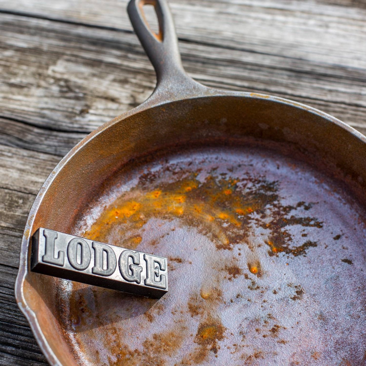 Black rust eraser bar embossed with lettering, resting on a heavily rusted cast iron skillet, illustrating a cleaning utensil from Kitchen & Food and Household Cleaning collections made in USA.
