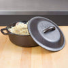 Handcrafted cast iron Dutch oven with a fitted lid embossed with the brand name, shown with baked dish inside, ideal for Kitchen & Food, Cookware, Cast Iron, USA Made, and Best Sellers collections.
