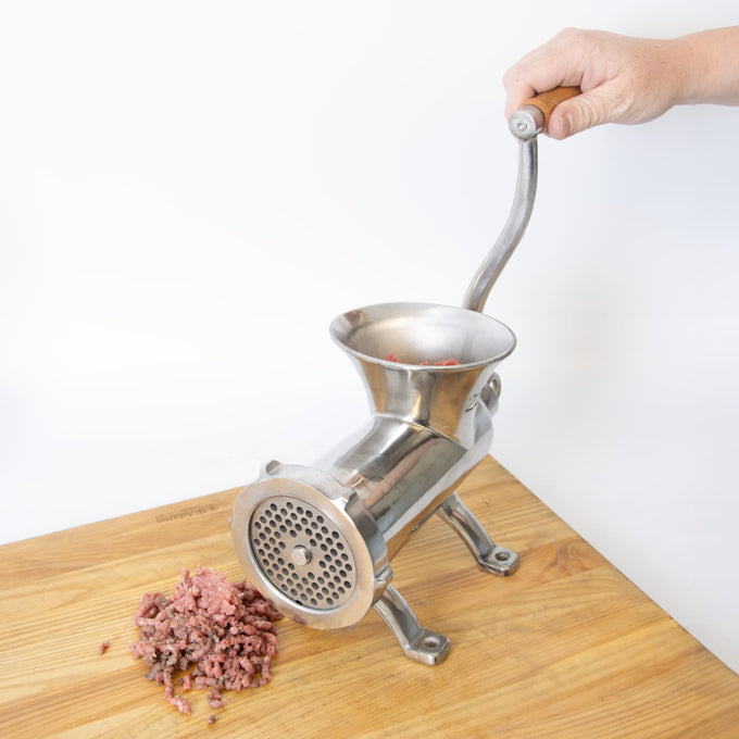 Hand turning a handcrafted stainless steel mounted meat grinder with wooden handle, mounted securely on a wooden surface, processing fresh ground meat in Kitchen & Food, Specialty Equipment, Butchering Supplies, Best Sellers, Promo Eligible collections.