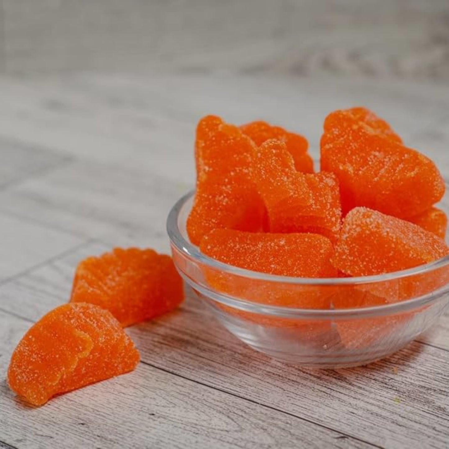 Clear glass bowl filled with bright orange sugar-coated slice candies with a chewy texture, evoking nostalgic flavors from Kitchen & Food, Food, Snacks and Sweets, Best Sellers, and Promo Eligible collections.
