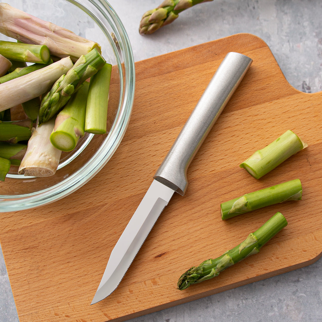 Handcrafted serrated paring knife with a fine stainless steel blade and solid aluminum handle, made in USA, resting on a wooden cutting board with trimmed asparagus, ideal for Farm, Garden & Tool and Kitchen & Food collections.