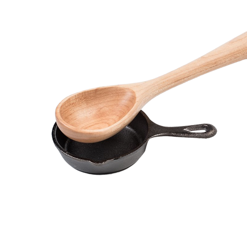 Wooden spoon resting inside a small pre-seasoned cast iron skillet, showcasing classic kitchen tools ideal for cookware, cast iron, and kitchen accessories collections.