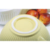 Bottom view of a soft butter yellow Grip-EZ mixing bowl with a non-slip base and textured exterior, shown near fresh nectarines alongside a white mixing bowl in Kitchen & Food and Baking Supplies.