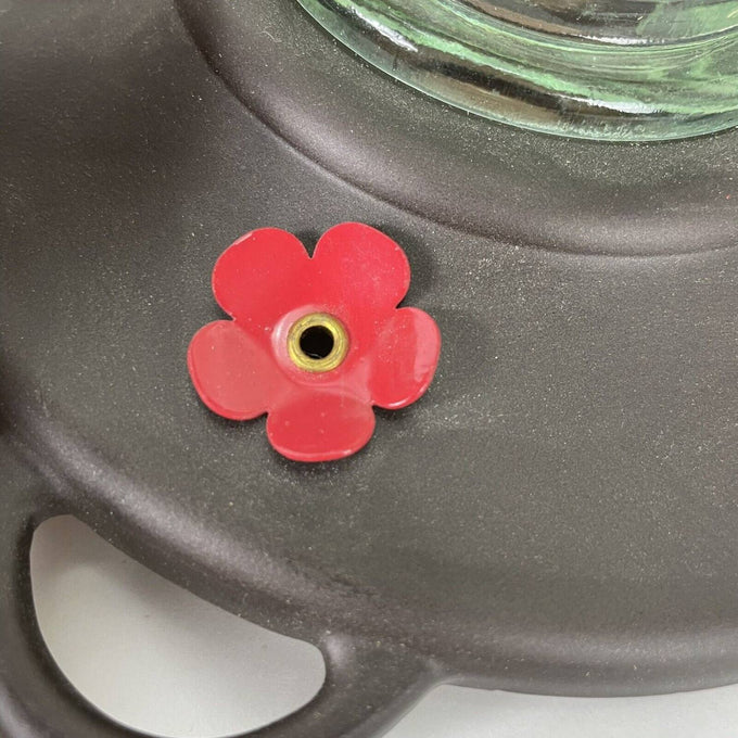 Close-up of a burnt penny plastic base with a red flower-shaped feeding port on a vintage-style clear glass hummingbird feeder, part of Farm, Garden & Tool and Animal Care collections.
