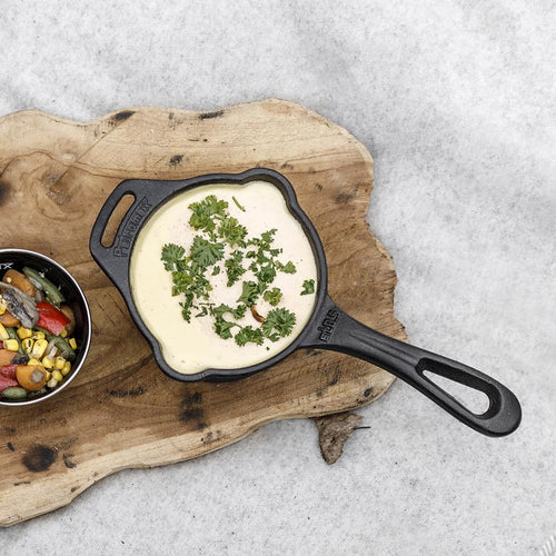 Cast iron sauce pot with long handle and side loop filled with creamy sauce garnished with fresh herbs, shown on rustic wooden board, ideal for Farm, Garden & Tool, Kitchen & Food, Camping, Cookware, Cast Iron, and Best Sellers collections.