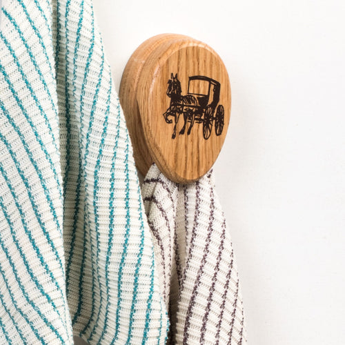 Handcrafted oak towel holder with protective clear finish featuring a horse and buggy design, with adhesive backing for easy installation, ideal for Home & Decor, Household Helpers, USA Made, and Amish Made collections.