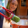 Person using a red and white one-handed jar lifter to safely remove a glass jar filled with green beans from a pot, part of Kitchen & Food and Canning Accessories collections.