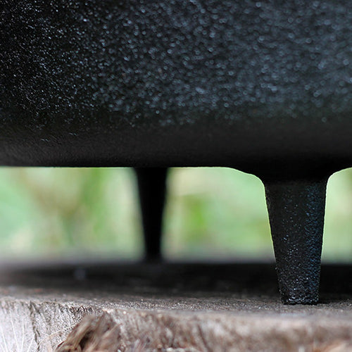 Close-up of sturdy cast iron legs supporting a heavy-duty pot on a wooden surface, highlighting durable craftsmanship for Kitchen & Food, Cookware, Cast Iron, Best Sellers, and Promo Eligible collections.