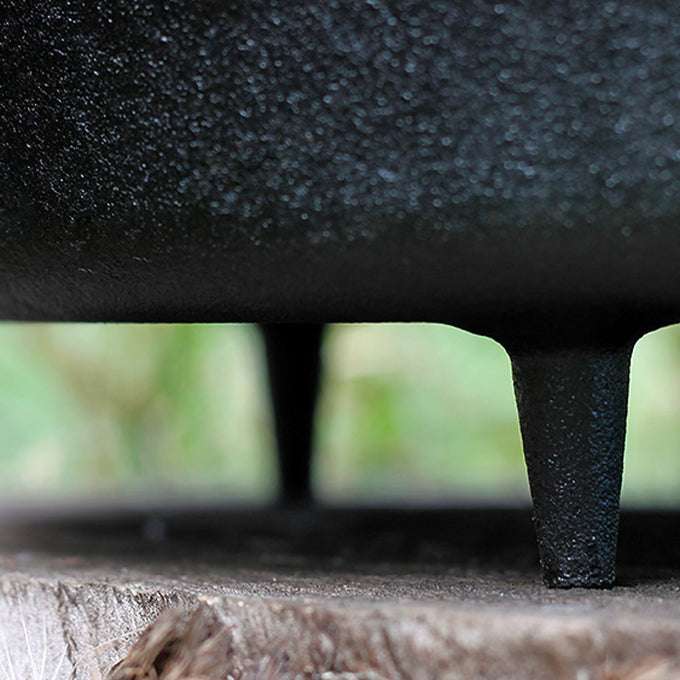 Close-up of sturdy cast iron legs supporting a heavy-duty pot on a wooden surface, highlighting durable craftsmanship for Kitchen & Food, Cookware, Cast Iron, Best Sellers, and Promo Eligible collections.
