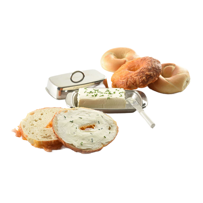 Polished stainless steel butter dish with matching cover, holding a block of cream cheese topped with herbs, styled with bagels and a bread slice spread with cream cheese, ideal for Kitchen & Food and Specialty Equipment collections.