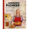 Smiling woman in a checkered shirt and red apron holding a roasted chicken on a red platter, standing in a bright traditional kitchen with cookies, broth jar, and vintage decor, part of handcrafted Amish made cookbooks in the Books and Best Sellers collections.