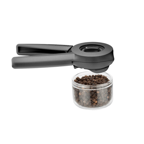 Matte black Ortwo Lite Salt and Pepper Mill with ergonomic dual handles positioned above a clear container filled with whole black peppercorns, designed for Kitchen & Food, Dinnerware, Kitchen Gadgets, Cooking and Baking Helpers, and Storage and Serving collections.