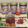 Three jars of handcrafted no sugar added jams in peach, rhubarb-strawberry, and seedless red raspberry flavors displayed on a wooden crate, with fresh strawberries, a glass jar, and a slice of bread topped with jam, ideal for Kitchen & Food and USA Made collections.
