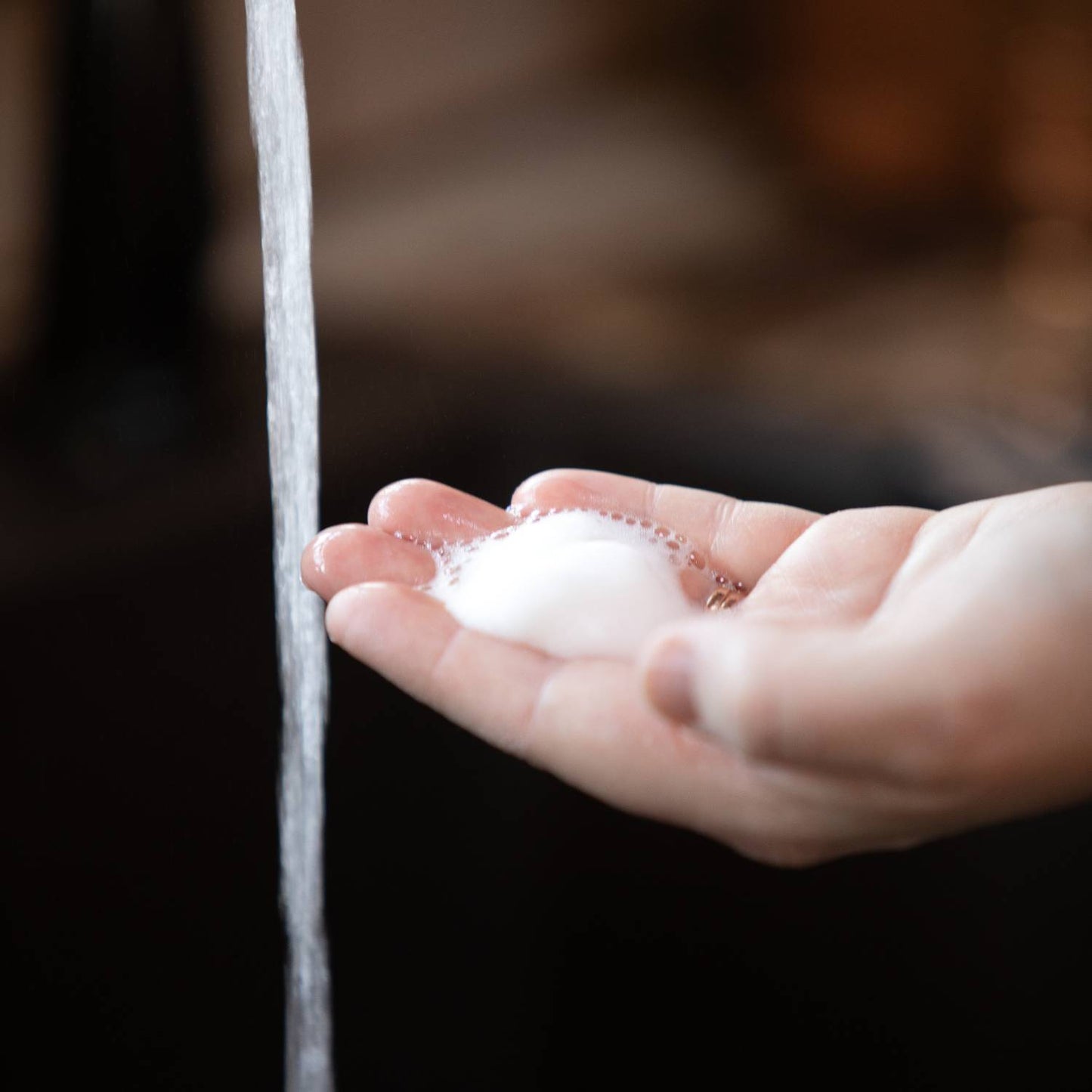 Hand holding rich foam from Lehman's handcrafted moisturizing foaming soap beneath running water, highlighting gentle cleansing in Health & Wellness and Grooming collections.