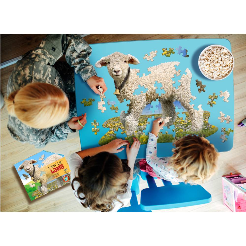 Children and an adult working together on a handcrafted lamb-shaped puzzle with large pieces, featuring playful farm scenery, popcorn nearby, promoting Toys, Books & Games collections.
