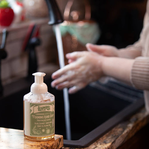 Lehman's Castile foaming hand soap bottle on kitchen counter with hands being washed under running water, natural moisturizing formula for Health & Wellness and Grooming collections