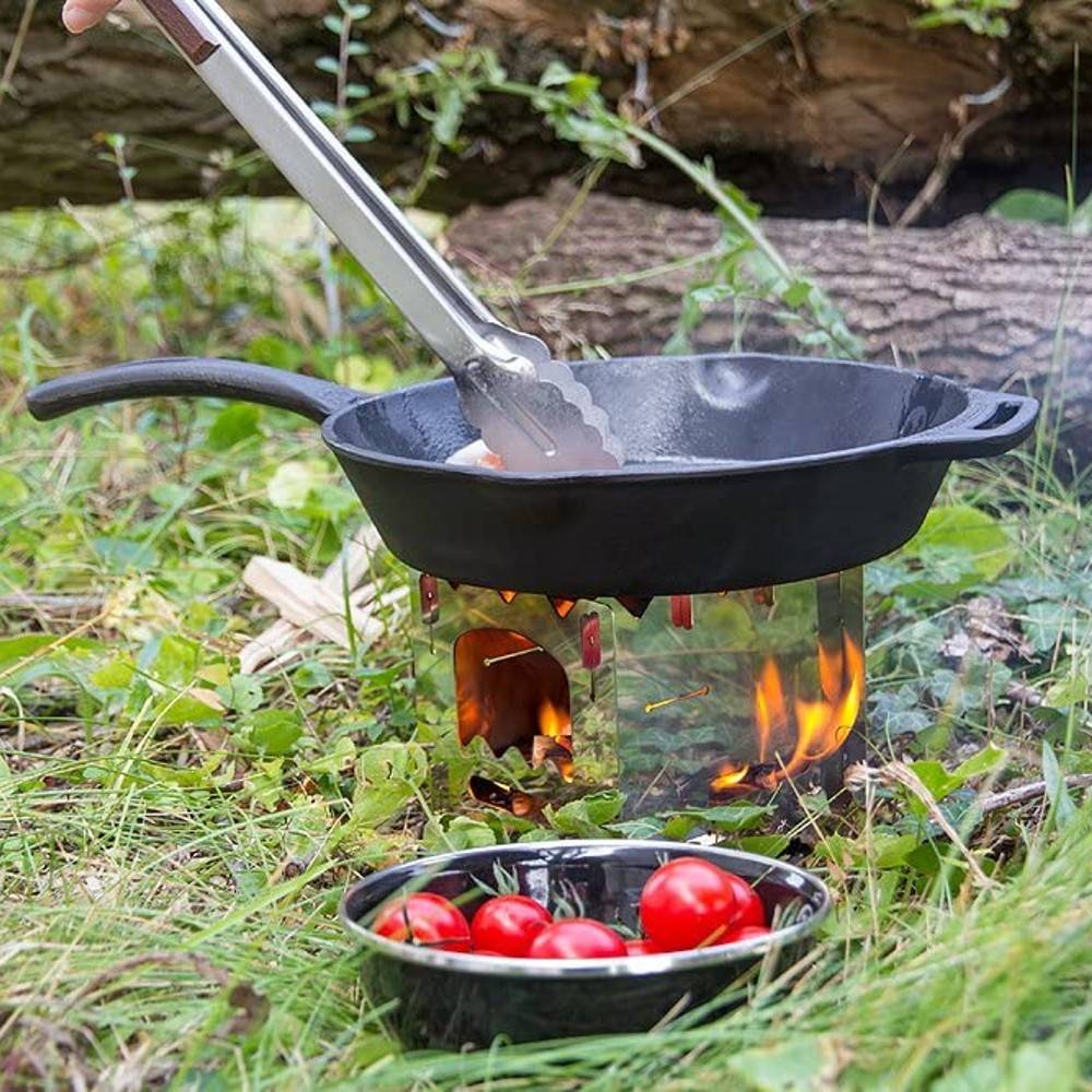 Cast iron skillet with long handle cooking over an open flame on a portable stove in a grassy outdoor setting, accompanied by a bowl of fresh cherry tomatoes, featured in Farm, Garden & Tool, Camping, Kitchen & Food, Cookware, Cast Iron, and Best Sellers collections.
