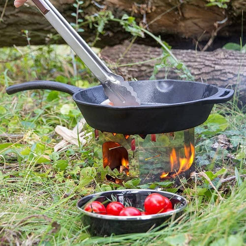 Cast iron skillet with long handle cooking over an open flame on a portable stove in a grassy outdoor setting, accompanied by a bowl of fresh cherry tomatoes, featured in Farm, Garden & Tool, Camping, Kitchen & Food, Cookware, Cast Iron, and Best Sellers collections.