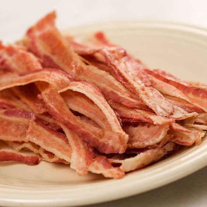 Stack of ready-to-eat, hand-rolled strips of savory bacon on a cream-colored plate, ideal for Kitchen & Food, Camping, Emergency Supplies, and Meats collections.