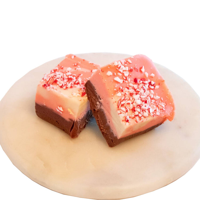 Two handcrafted layered fudge squares with rich chocolate bottoms, creamy white centers, and pink tops sprinkled with crushed peppermint, featured in Kitchen & Food, USA Made, and Best Sellers collections.