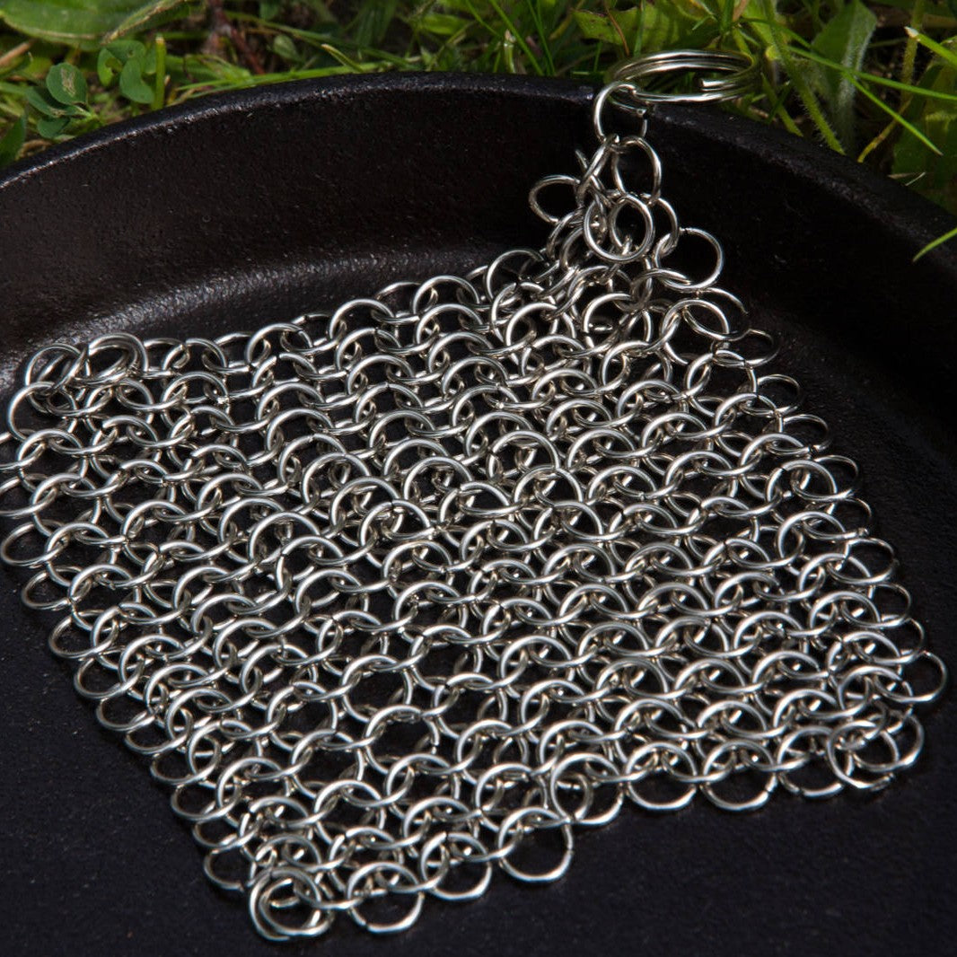 Petromax chainmail cleaner made of stainless steel rings with keyring handle resting on a cast iron skillet outdoors, featured in Home & Decor, Household Cleaning, and Cleaning Utensils collections.