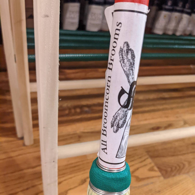 Close-up of a handcrafted Amish made broom handle with a green fabric wrap and a paper label reading "All Broomcorn Brooms," featured in Home & Decor, Cleaning Utensils and USA Made collections.