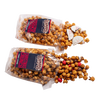 Two clear bags of handcrafted caramel popcorn with holiday-themed additions spilling out, including white chocolate peppermint bark pieces and red candy, for Kitchen & Food, Snacks and Sweets, Popcorn, and Best Sellers collections.