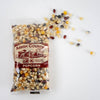 Clear plastic bag of multicolored Amish Country popcorn kernels spilling onto a white surface, highlighting handcrafted, USA made popcorn in Kitchen & Food and Snacks collections.