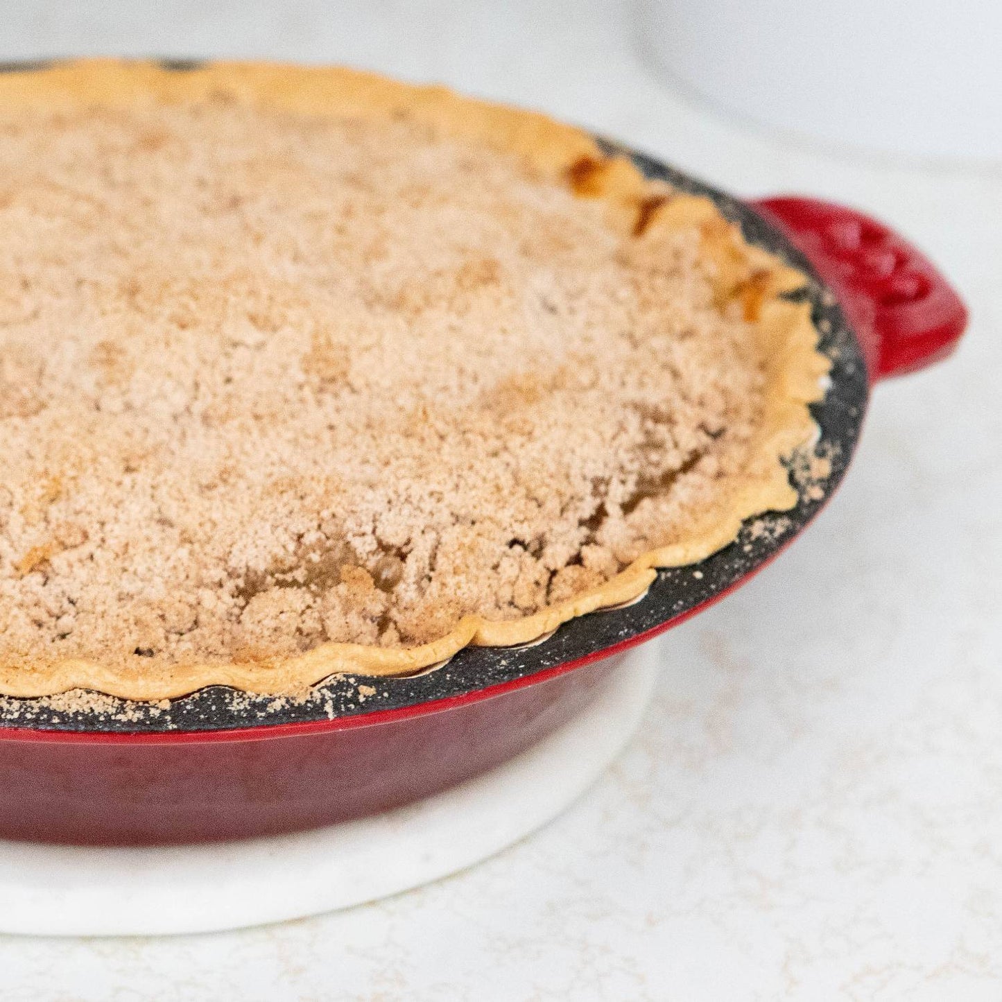 Handcrafted cast iron pie pan with crimped edges baking a crumb-topped pie, featuring durable even heat for kitchen & food, cookware, cast iron, baking supplies, and best sellers collections.