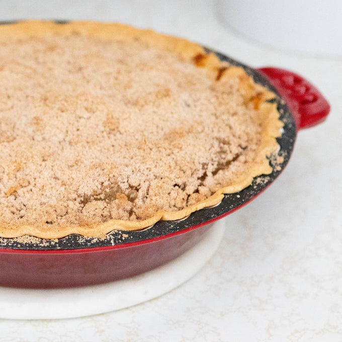 Handcrafted cast iron pie pan with crimped edges baking a crumb-topped pie, featuring durable even heat for kitchen & food, cookware, cast iron, baking supplies, and best sellers collections.