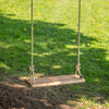 Handcrafted wooden rectangle swing seat with natural rope hanging outdoors on green grass, part of USA Made, Wooden Toys, Children's Toys, and Outdoor Play collections.