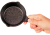 Hand holding a pre-seasoned mini cast iron skillet with textured cooking surface and small handle, ideal for kitchen gadgets and cast iron cookware collections.