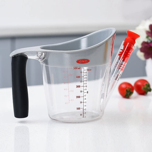 Clear plastic fat separator with soft black grip handle, gray rim, red stopper, and measurement markings, designed for easy pouring and fat separation in Kitchen & Food and Cooking Helpers collections.