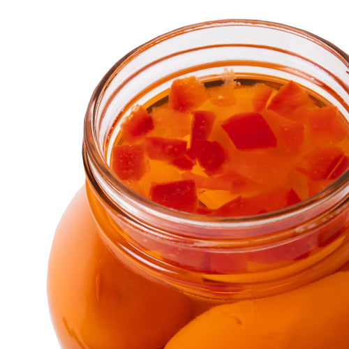 Close-up of a glass jar filled with hot pickled eggs in spicy orange brine with visible red pepper pieces, locally made and featured in Kitchen & Food, Pantry, USA Made, and Best Sellers collections.