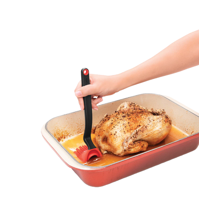 Black silicone brush with flexible head and ergonomic handle, designed to scoop and release liquids efficiently while basting roasted chicken, ideal for Kitchen & Food, Stoves, and Grilling collections.