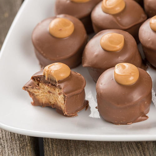 Close-up of handmade chocolate peanut butter confections with smooth chocolate coating and creamy peanut butter centers, presented on a white plate, part of Kitchen & Food and USA Made collections.