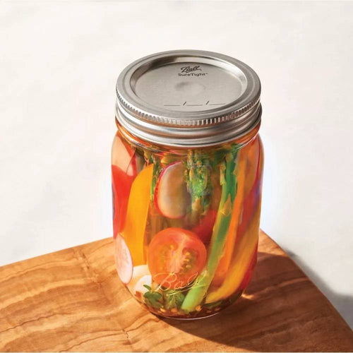 Glass jar sealed with a metal lid containing assorted colorful pickled vegetables, showcased on a wooden surface, highlighting quality canning supplies in Kitchen & Food and Food Preservation collections.
