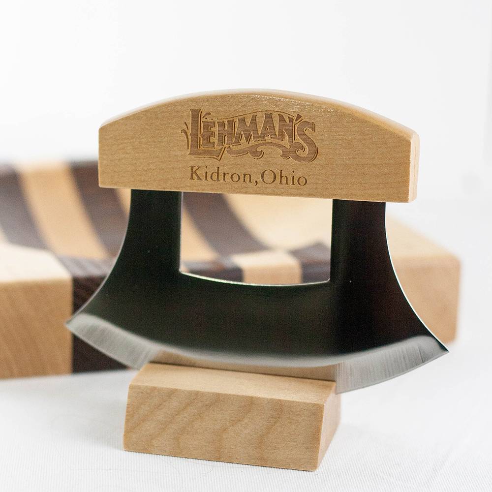 Handcrafted curved chopping knife with wooden handle engraved Lehman’s Kidron Ohio, displayed on wooden stand with striped cutting board in background, ideal for Farm, Garden & Tool and Kitchen Knives collections.