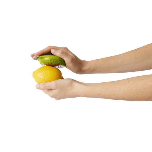 Person holding a green ergonomic citrus zester over a lemon, demonstrating easy zesting for Kitchen & Food, Kitchen Gadgets, Cooking and Baking Helpers, and Best Sellers collections.