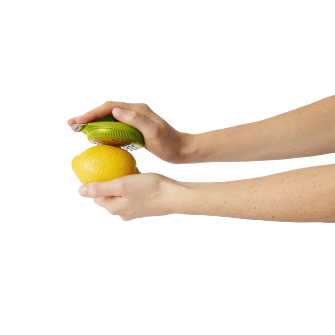 Person holding a green ergonomic citrus zester over a lemon, demonstrating easy zesting for Kitchen & Food, Kitchen Gadgets, Cooking and Baking Helpers, and Best Sellers collections.